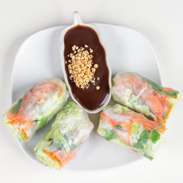Four fresh Thai spring rolls with shrimp and vegetables, served with peanut dipping sauce.