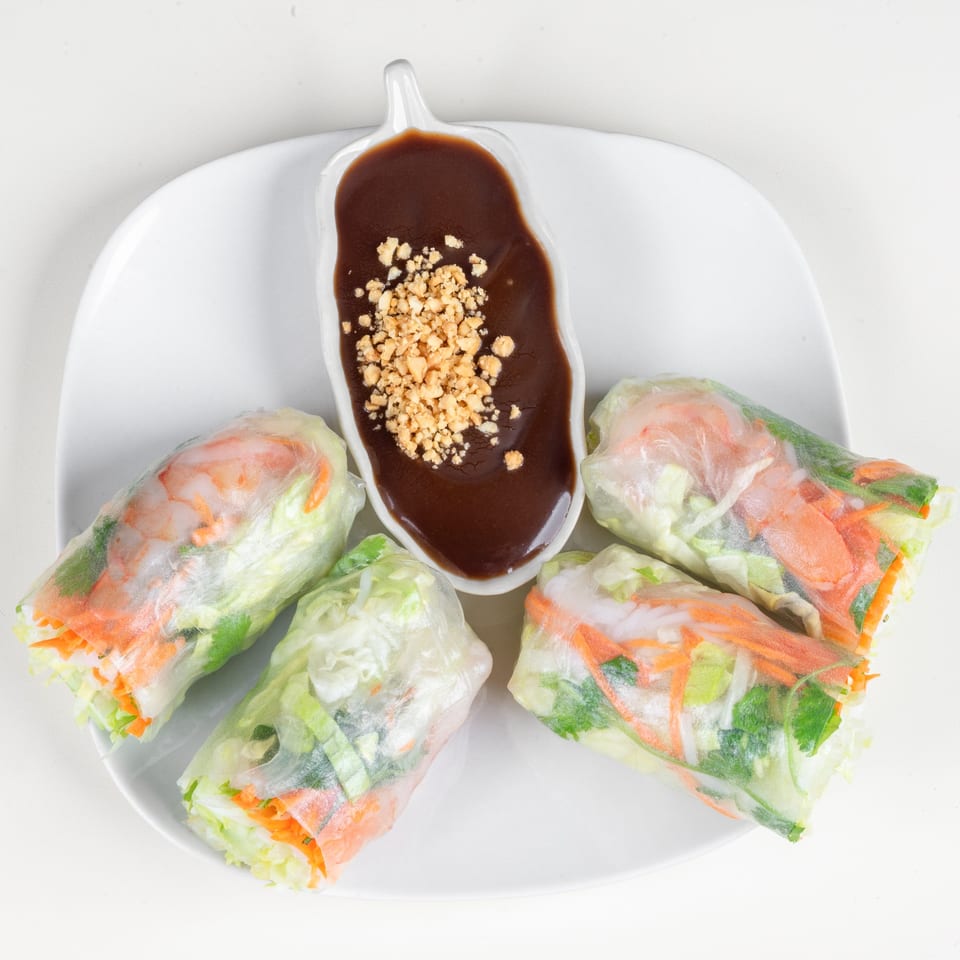 Four fresh Thai spring rolls with shrimp and vegetables, served with peanut dipping sauce.