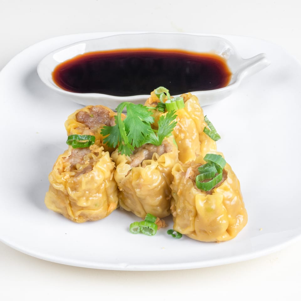 Simply Asian Thai Restaurant's steamed dumplings with cilantro and scallions, served with a side of soy sauce.